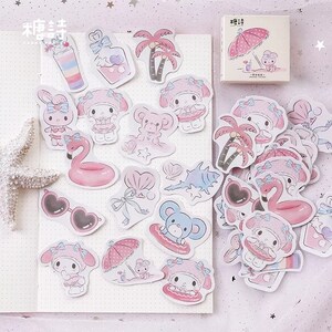 K&ouml;nnte beinhalten: Ein Set mit rosa und wei&szlig;en Aufklebern, die einen Comic-Charakter mit einer rosa Schleife und eine Vielzahl von sommerlichen Designs zeigen, darunter Palmen, Sonnenbrillen und ein Flamingo-Schwimmring.