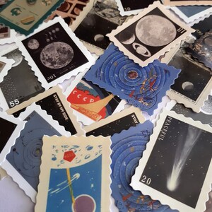 May include: A collection of vintage space-themed postage stamps featuring images of the moon, planets, and comets. The stamps are printed on blue, white, and black paper with various text, including "THE MOON 10c", "THE EARTH AS MEN", "CCCP", "STAY BY MY SIDE", "PEACEFUL", "STAY", and "16561-6-11".