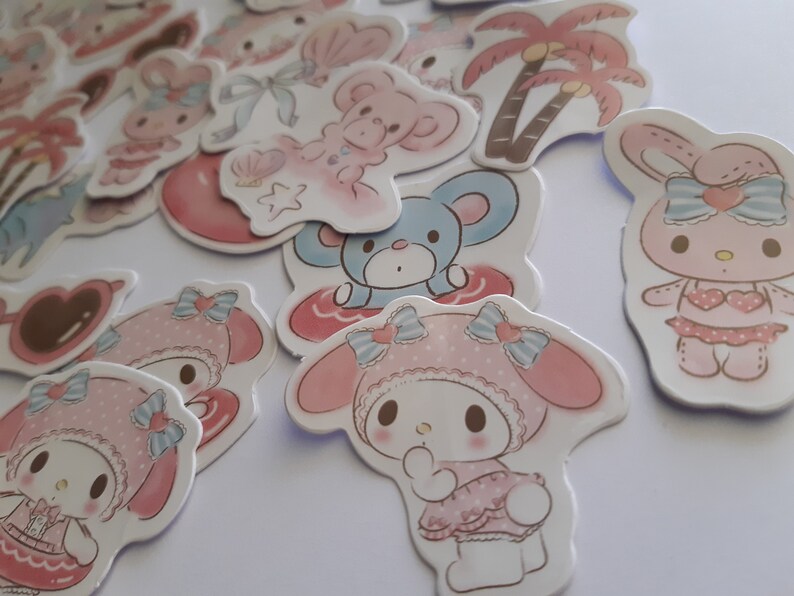 K&ouml;nnte beinhalten: Ein Set mit bunten Aufklebern mit Comicfiguren. Die Aufkleber sind rosa, blau und wei&szlig; und zeigen Figuren mit Schleifen, Herzen und Blumen. Die Aufkleber sind perfekt, um Ihrem Planer, Tagebuch oder Laptop einen Hauch von Verspieltheit zu verleihen.