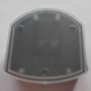 May include: A clear plastic case with a black interior and five small holes around the edge.