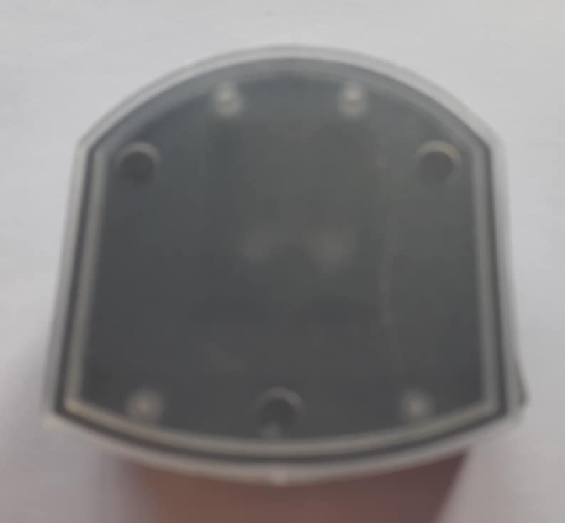 May include: A clear plastic case with a black interior and five small holes around the edge.