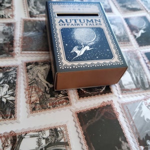 May include: A blue box with a white border and the text "Autumn of Fairy Tales" on the front. The box is decorated with a white silhouette of a horse and rider against a starry night sky.