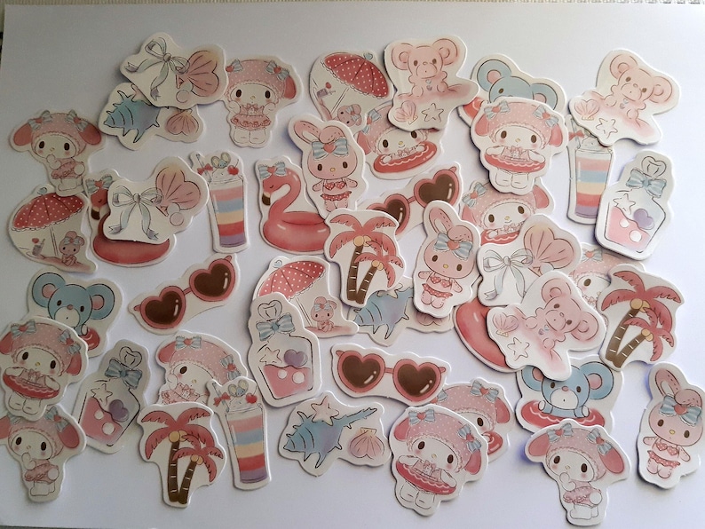 K&ouml;nnte beinhalten: Eine Sammlung von rosa und wei&szlig;en Aufklebern mit Comicfiguren, Palmen, Sonnenbrillen und anderen sommerlichen Designs.