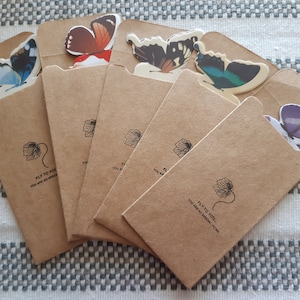 May include: Six brown paper envelopes with butterfly cutouts on the front. Each envelope has a black and white floral design and the text "Fly to you! You are so special to me."