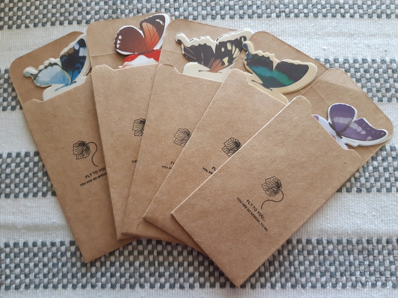 May include: Six brown paper envelopes with butterfly cutouts on the front. Each envelope has a black and white floral design and the text "Fly to you! You are so special to me."