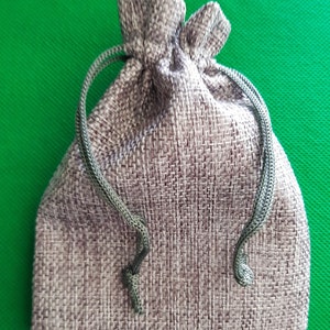 May include: A small, gray drawstring bag made of burlap fabric with a green drawstring.