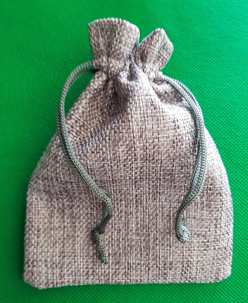 May include: A small, gray drawstring bag made of burlap fabric with a green drawstring.