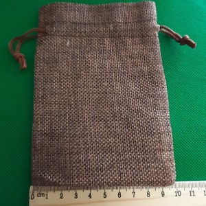 May include: A small brown burlap drawstring bag with a brown cord. The bag is about 9 inches wide and 11 inches tall.