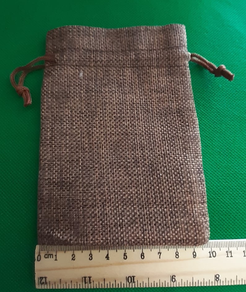 May include: A small brown burlap drawstring bag with a brown cord. The bag is about 9 inches wide and 11 inches tall.