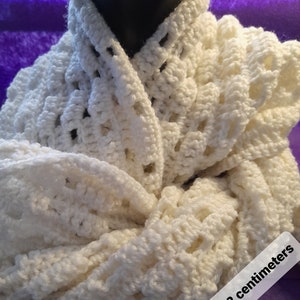 May include: White crocheted infinity scarf with a delicate openwork pattern. The scarf measures 165 x 22 centimetres.