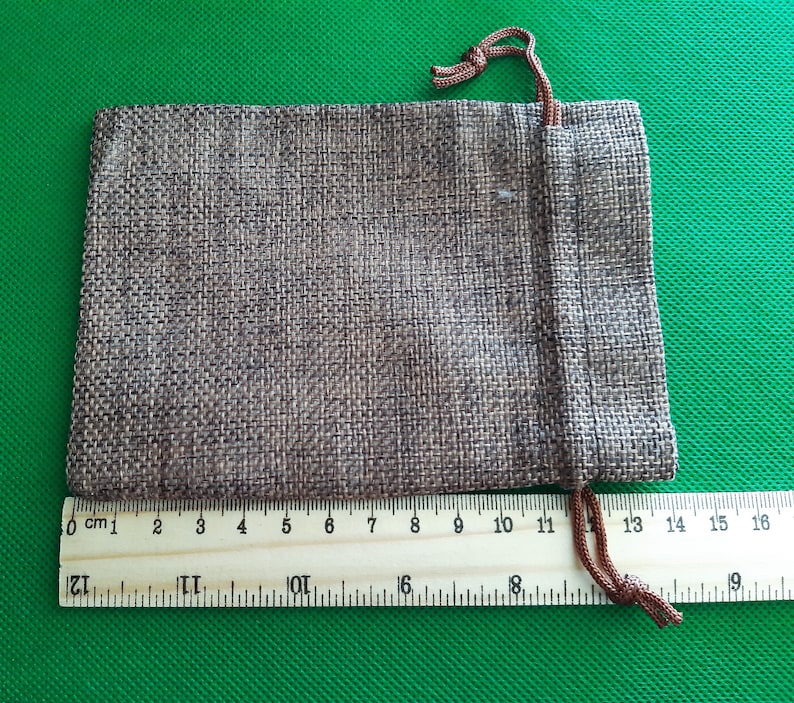 May include: A brown burlap drawstring pouch with a brown cord. The pouch is 13 cm wide and 10 cm tall.