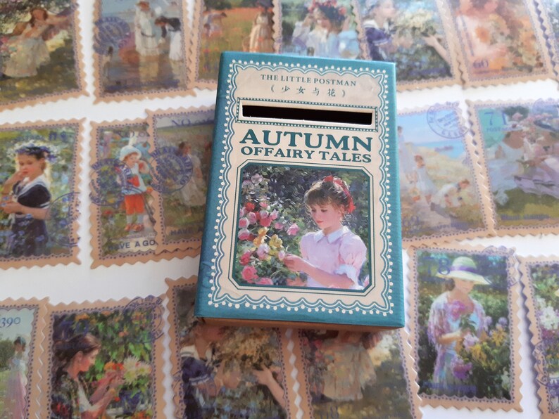 May include: A teal blue box with a slot on the top. The box has a picture of a girl in a pink dress holding a flower. The text on the box reads "The Little Postman (少女与花) Autumn Offairy Tales".