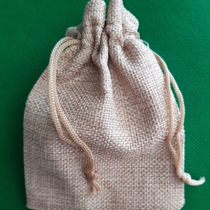 May include: A small, brown burlap drawstring bag with a gathered top. The bag is made of a natural, woven fabric and has a rustic, earthy look.
