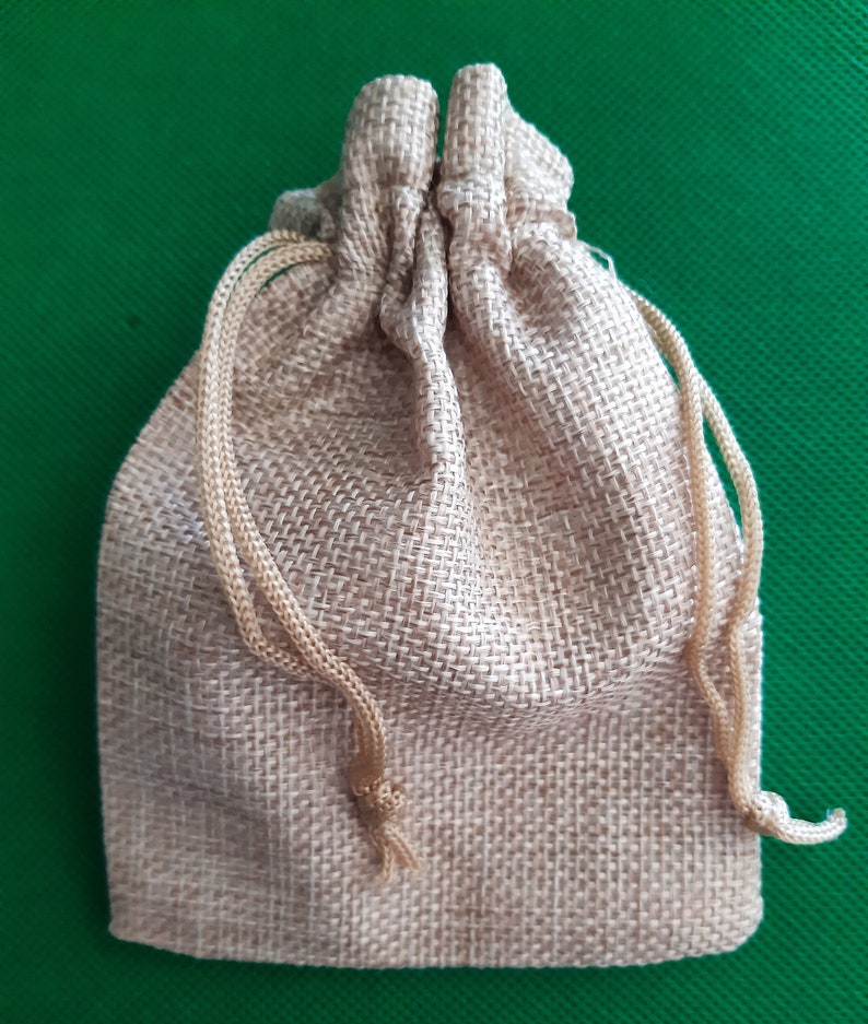 May include: A small, brown burlap drawstring bag with a gathered top. The bag is made of a natural, woven fabric and has a rustic, earthy look.
