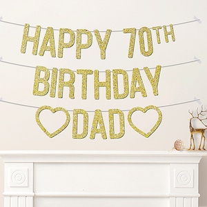 May include: Gold glitter banner with the text "Happy 70th Birthday Dad" with hearts on either side of the word "Dad".
