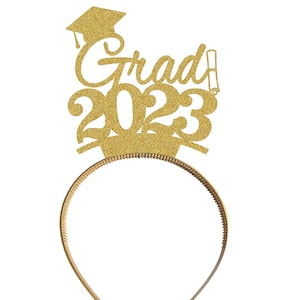 May include: Gold glitter headband with a graduation cap, the word "Grad" and the year "2023".