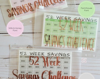 May include: Three clear plastic envelopes with rose gold vinyl lettering that reads "52 Week Savings Challenge". Each envelope has a different font style: Milk & Honey, Farmhouse, and Calligraphy.