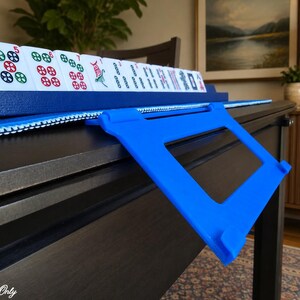 Blue foldable 3D printed PLA hands-free mahjong card holder, slim compact footprint ideal for small card tables and tight game setups.
