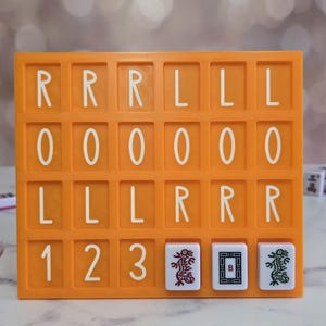 May include: An orange Mahjong tile holder with white letter and number tiles. The tiles spell out "RRRLLLL", "0000000", and "LLLLRRR". Three Mahjong tiles with dragon and character designs are at the bottom.