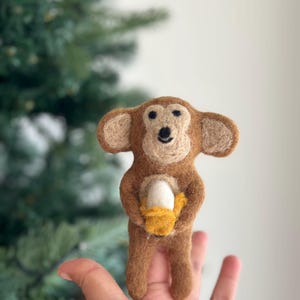 May include: A brown felt monkey holding a yellow felt basket with a white felt egg inside.