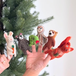 May include: A set of six felt finger puppets featuring woodland animals. The puppets include a rabbit, a raccoon, a snake, an owl, a red panda, and a squirrel. The puppets are all made of soft, colorful felt and are perfect for imaginative play.