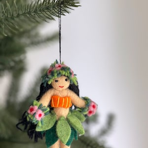 A felt ornament of a hula dancer with a green lei, orange top, and green grass skirt. The ornament has black hair and a smiling face.