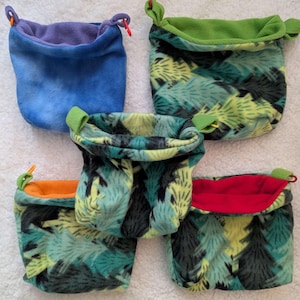 May include: Five fleece pouches in various colors and patterns. One is blue with a purple interior, another has a green exterior and interior, and three feature a green and black tree pattern. Each has a loop for hanging.