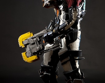 May include: A detailed cosplay of a futuristic space suit with a helmet, armor, and a large yellow and gray weapon. The suit is primarily white, black, and gray, with red and yellow accents. The overall design suggests a science fiction or video game theme.