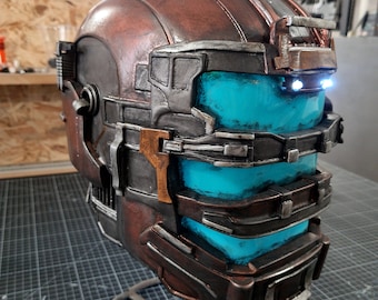 May include: A detailed, weathered brown and silver helmet with glowing blue visor panels. The helmet has a complex, layered design with visible rivets and a metallic finish, suggesting a futuristic or sci-fi theme.