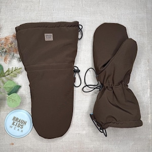 May include: Brown winter mittens with a drawstring closure and a small label that reads "BRAUN KIDS WEAR". The mittens are made of a durable, water-resistant material, perfect for cold weather. A matching brown mitten is also shown.