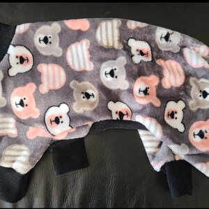May include: A gray and pink dog pajamas with a bear print. The pajamas have black trim around the neck and cuffs.