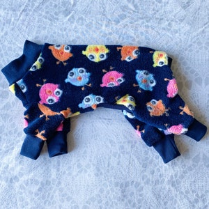 May include: A navy blue dog pajamas with a colorful owl print. The pajamas have a turtleneck and long sleeves.