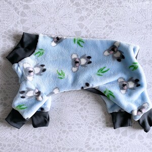 May include: A blue fleece dog onesie with a koala bear print and black trim.