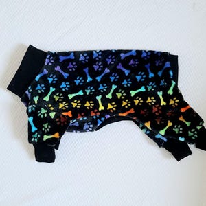 May include: Black dog pajamas with a rainbow bone and paw print pattern.