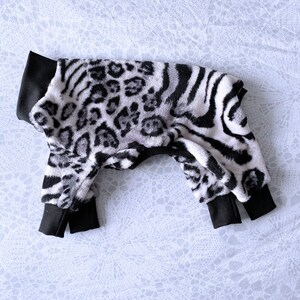 May include: A black and white zebra and leopard print dog jumpsuit with black ribbed cuffs.