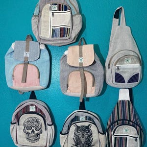May include: Collection of hemp backpacks and sling bags in various designs. Some feature colorful woven patterns, while others display a skull and an owl graphic. The bags have adjustable straps and multiple pockets. The color palette includes beige, blue, pink, and gray.