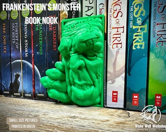 Könnte beinhalten: Ein leuchtend grüner, 3D-gedruckter Buchstützen-Einsatz mit einem skulpturalen Relief von Frankensteins Monster. Das rechteckige Objekt zeigt das Gesicht der Kreatur mit markanten Nähten, einer schweren Stirn und einer Hand nahe dem Kinn.