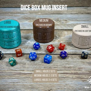 May include: Image of three dice box mug inserts in varying sizes and colors, with several polyhedral dice scattered around. The inserts are labeled "Large" (diamond green), "Medium" (brown), and "Small" (light brown). Text on the image reads "Dice Box Mug Insert."