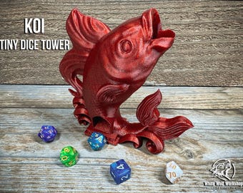 Könnte beinhalten: Ein roter Koi-Fisch-förmiger Mini-Würfelturm mit dem Text "KOI TINY DICE TOWER". Der Turm ist von bunten Würfeln umgeben. Der Fisch hat detaillierte Flossen und einen offenen Mund. Die Würfel sind blau, grün und weiß.