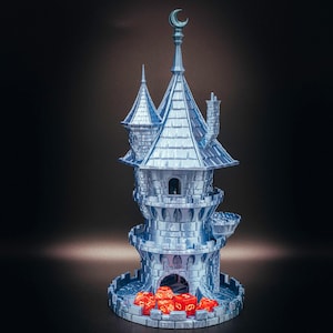 May include: A silver-colored dice tower shaped like a castle, with a crescent moon on top. The tower has multiple levels, turrets, and a chimney. Red dice are visible at the base. The White Wolf Workshops logo is in the lower right corner.