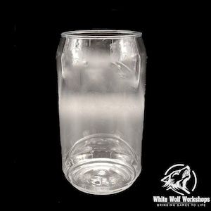May include: A clear, cylindrical drinking glass, shaped like a can. The glass has a rounded base and a slightly flared top. The surface is smooth and transparent, with a frosted appearance in the middle. The glass is set against a black background.
