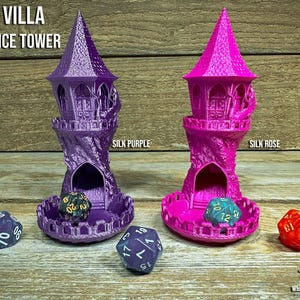 May include: Two miniature dice towers in the image, one silk purple and one silk rose, each with a castle-like design. The towers have a cone-shaped top and a circular base. The text "FEY VILLA TINY DICE TOWER" is at the top. Several dice are placed around the towers.