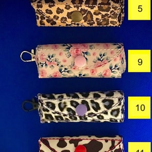 May include: Four different keychains with various patterns. The keychains are made of fabric and have a metal ring. The patterns include leopard print, floral, cow print, and another leopard print. The keychains are numbered 5, 9, 10, and 11.