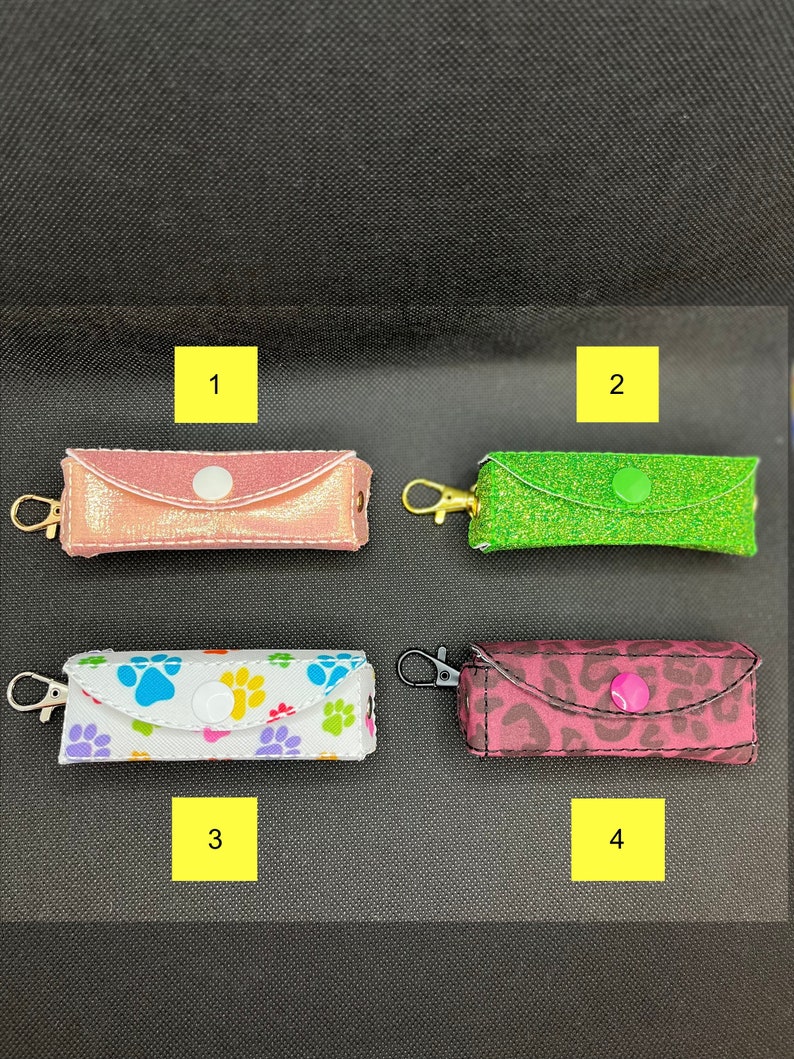 May include: Four different styles of small zippered pouches with key rings. The pouches are pink with gold glitter, green with green glitter, white with colorful paw prints, and pink with a leopard print.