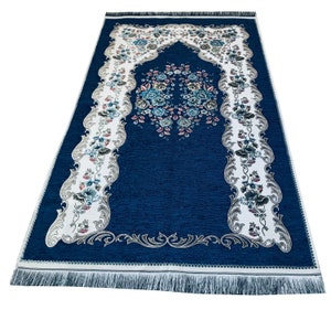 May include: A blue prayer rug with a white border and floral design. The rug has a fringed edge and a decorative arch in the center.