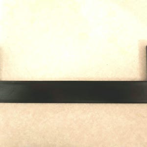 May include: A black plastic shelf bracket with a textured surface and a series of small teeth along the edges.