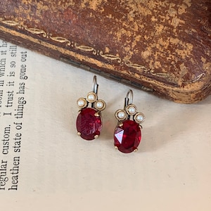 May include: A pair of red gemstone earrings with a silver setting and white pearl accents.