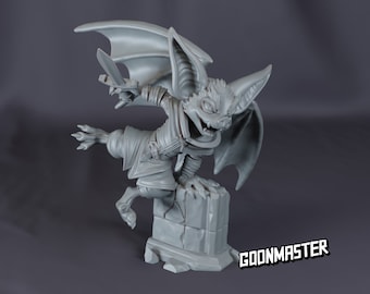 May include: A gray painted miniature figurine of a bat-like creature with wings, holding a sword and standing on a stone base. The base has a rough texture and is sculpted with cracks. The figurine is labeled "GOONMASTER".