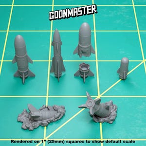 May include: A set of six gray plastic miniature rockets, some with fins and some with a rounded nose, rendered on a green grid background.  The text "GOONMASTER" is visible in the top center of the image.