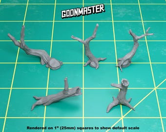 May include: Five gray miniature tree stumps and fallen logs with textured bark details. The text GOONMASTER is at the top. The objects are positioned on a green grid with 1-inch squares to show scale. These are unpainted plastic gaming terrain pieces.